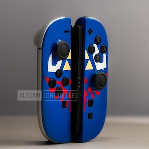 Puede incluir: Mandos de videojuegos azules y plateados con botones negros y un dise&ntilde;o personalizado. Los mandos presentan un dise&ntilde;o blanco y amarillo con detalles en rojo. El texto "XL TEAM CONTROLLERS" es visible.
