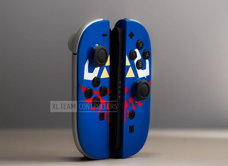 Puede incluir: Mandos de videojuegos azules y plateados con botones negros y un dise&ntilde;o personalizado. Los mandos presentan un dise&ntilde;o blanco y amarillo con detalles en rojo. El texto "XL TEAM CONTROLLERS" es visible.