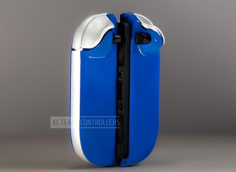 Puede incluir: Un mando de juego azul y plateado con un dise&ntilde;o elegante. El mando tiene un acabado azul brillante con detalles plateados en la parte superior y los laterales. El texto "XL TEA CONTROLLERS" est&aacute; impreso en el lateral.