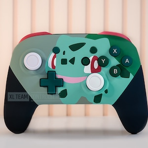 May include: A green, black, and red Nintendo Switch controller with a Bulbasaur design. The controller has the text "XL TEAM" on the left side.