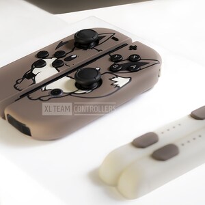 May include: A set of brown and white game controllers with a cartoon wolf design. The controllers have black buttons and joysticks. The text "XL TEAM CONTROLLERS" is visible on the side of the controller.
