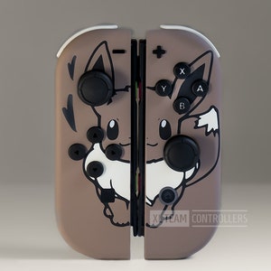 May include: Custom brown and white Nintendo Switch Joy-Con controllers featuring an Eevee design. The controllers have black buttons and joysticks, with the X-Team Controllers logo at the bottom.