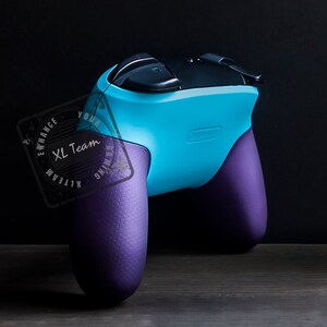 May include: A blue and purple video game controller with textured grips. The controller has a black top with buttons and a logo that says "Enhance Your Gaming XL Team".