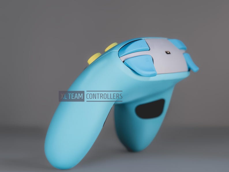 May include: A light blue video game controller featuring a silver top panel, light blue shoulder buttons, and yellow top buttons. The text XL TEAM CONTROLLERS is printed in a rectangular box on the side of the device handle.