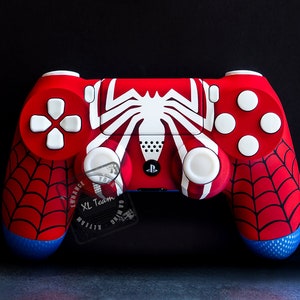 May include: A red and blue PlayStation 4 controller with a white spider web design. The controller has a blue and white logo on the front.