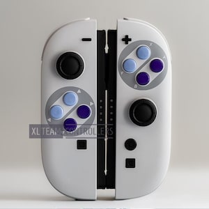 May include: White gaming controller with black and colored buttons. The controller has a retro design with blue and purple buttons. The text "XL TEAM CONTROLLERS" is visible on the bottom left.