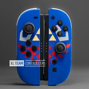 Puede incluir: Mandos Joy-Con XL TEAM CONTROLLERS azules y blancos con detalles en rojo y dorado. Los mandos tienen botones y joysticks negros, con el texto "XL TEAM CONTROLLERS" en blanco.