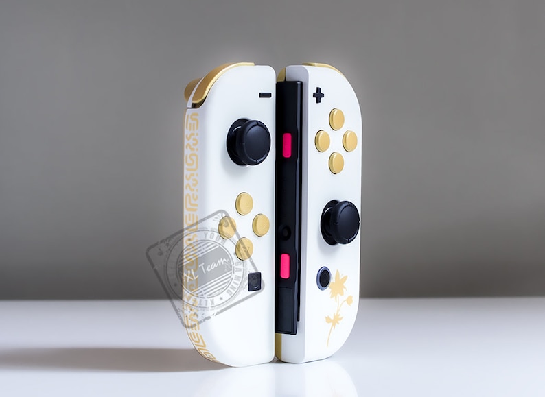 K&ouml;nnte beinhalten: Ein wei&szlig;er Nintendo Switch Joy-Con-Controller mit goldenen Akzenten und schwarzen Kn&ouml;pfen. Der Controller hat ein goldenes Muster an der Seite und ein goldenes Ahornblatt-Design auf der R&uuml;ckseite.