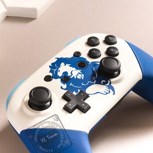 May include: A white and blue Nintendo Switch controller with a blue lion graphic and the text "XL Team".