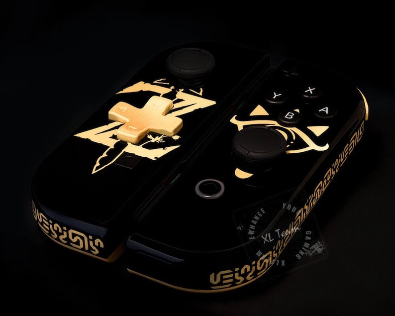 May include: Black Nintendo Switch console with a gold design featuring a sword and a Triforce symbol. The console has custom buttons and a gold d-pad.