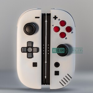 May include: White and black gaming controller with red buttons and a black joystick. The controller has a cross-shaped directional pad and the text "XL TEAM CONTROLLERS".