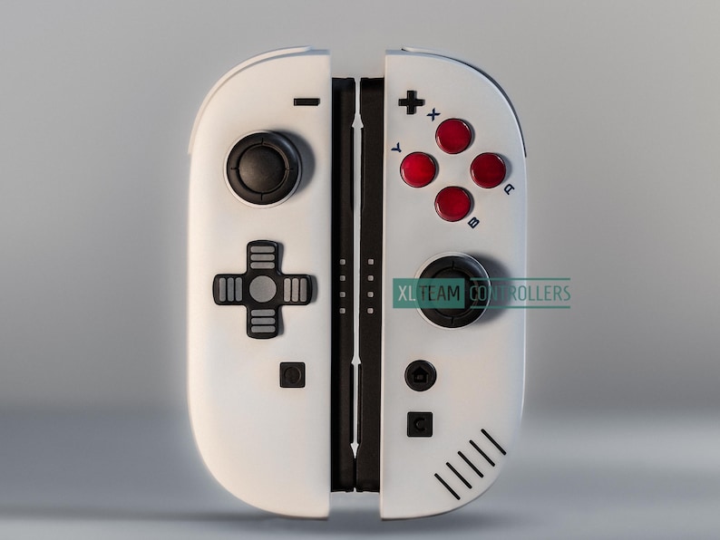 May include: White and black gaming controller with red buttons and a black joystick. The controller has a cross-shaped directional pad and the text "XL TEAM CONTROLLERS".