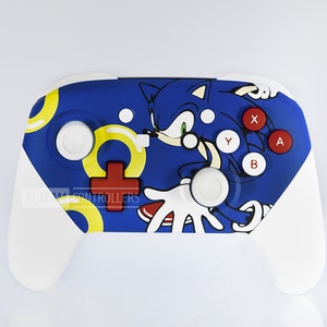 Puede incluir: Un mando blanco de Nintendo Switch con un diseño de Sonic the Hedgehog azul, amarillo y rojo. El mando tiene el texto "EXTREME CONTROLLERS".
