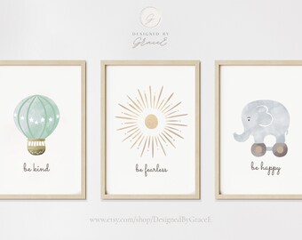 May include: Three framed prints with watercolor illustrations and inspirational messages. The first print features a green hot air balloon with white stars and the message "be kind". The second print features a gold sun with rays and the message "be fearless". The third print features a gray elephant on wheels and the message "be happy".