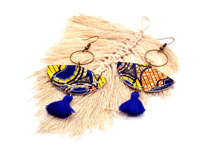 May include: A pair of colorful earrings with blue, yellow, and orange geometric patterns. The earrings have a gold hoop and a blue tassel.