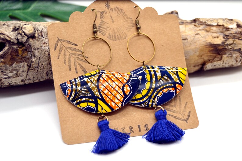 May include: A pair of colorful earrings with blue, yellow, orange, and brown geometric patterns. The earrings have gold hoops and blue tassels.