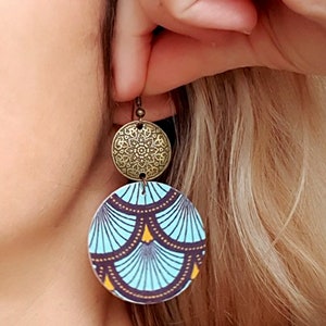 May include: A pair of dangle earrings with a blue and gold patterned circle and a smaller gold circle with a decorative design.