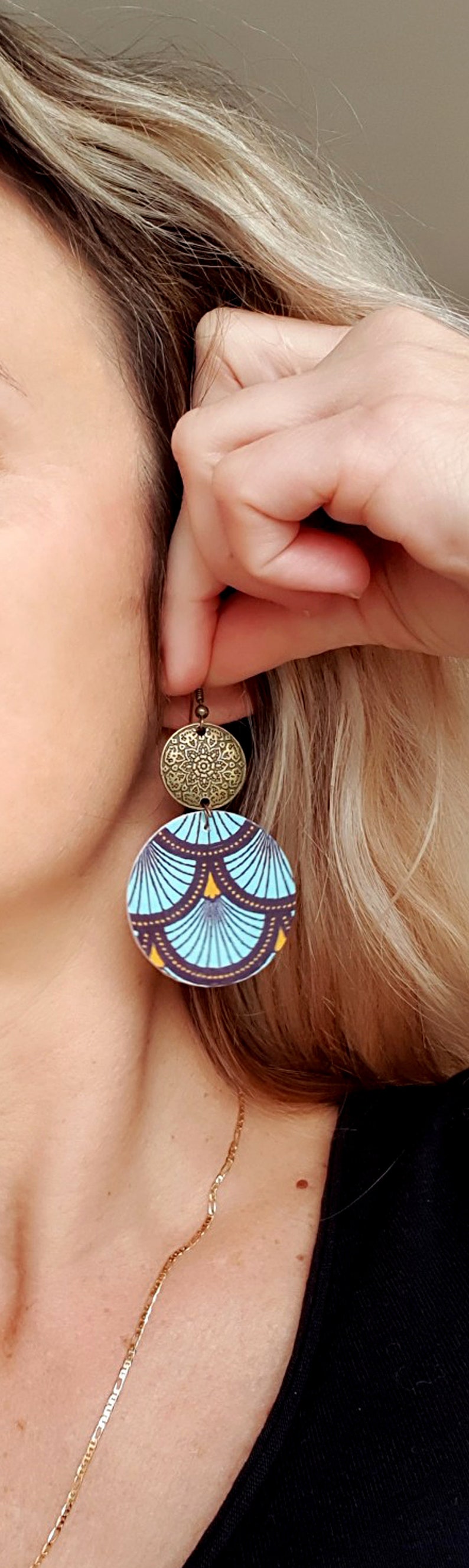 May include: A pair of dangle earrings with a blue and gold patterned circle and a smaller gold circle with a decorative design.