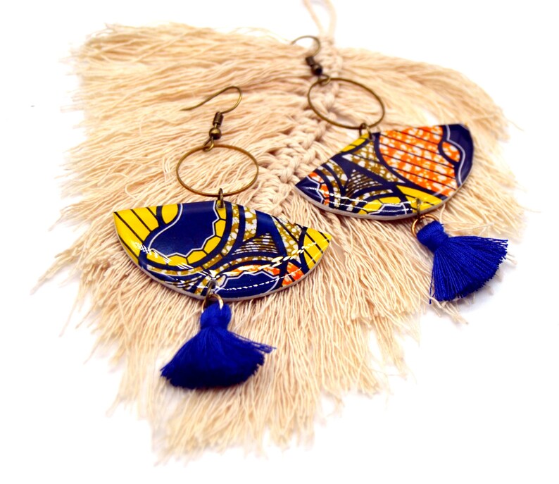 May include: A pair of colorful earrings with blue and yellow fabric patterns, gold hoops, and blue tassels.