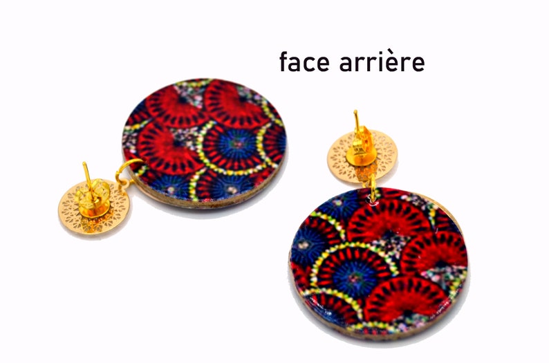 May include: A pair of gold tone earrings with round wooden discs featuring a colorful geometric pattern. The back of the earrings show the gold tone post and a circular back.