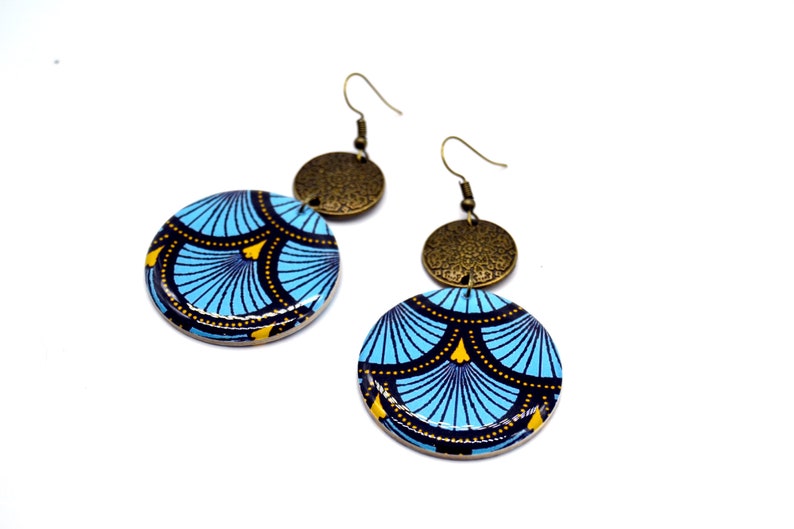 May include: A pair of blue and gold earrings with a geometric pattern. The earrings are made of wood and metal.