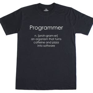 May include: Dark grey t-shirt featuring the word "Programmer" in white, with a definition below: "an organism that turns caffeine and pizza into software." The shirt has a crew neck and short sleeves.