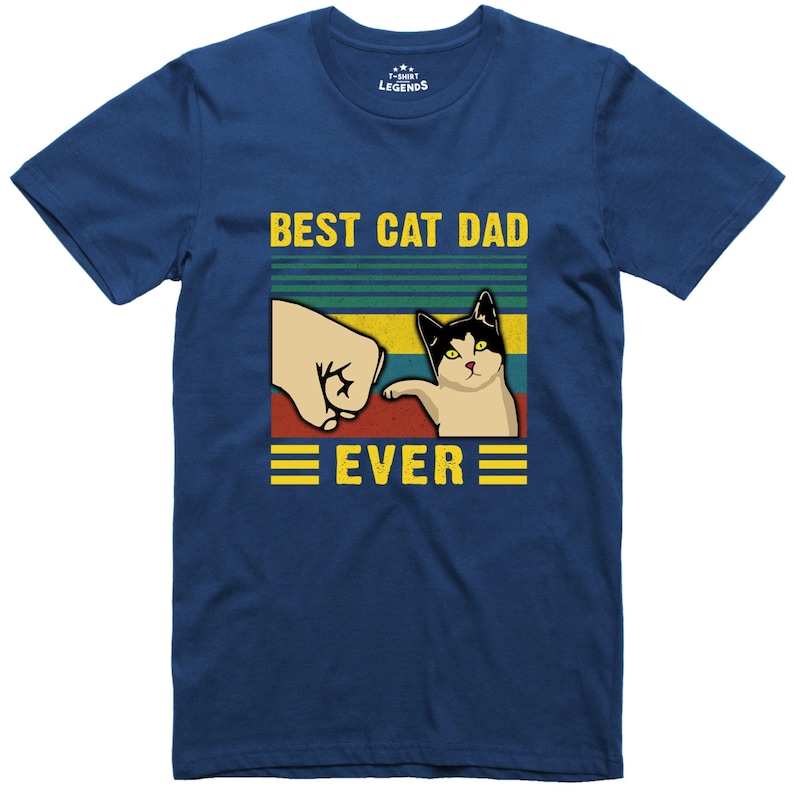 May include: A blue t-shirt with a retro-style graphic of a cat giving a fist bump to a hand. The text "BEST CAT DAD EVER" is printed in yellow on the shirt.