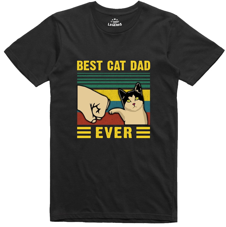 May include: Black t-shirt with a retro-style graphic that says "Best Cat Dad Ever". The graphic features a cat pawing at a fist.