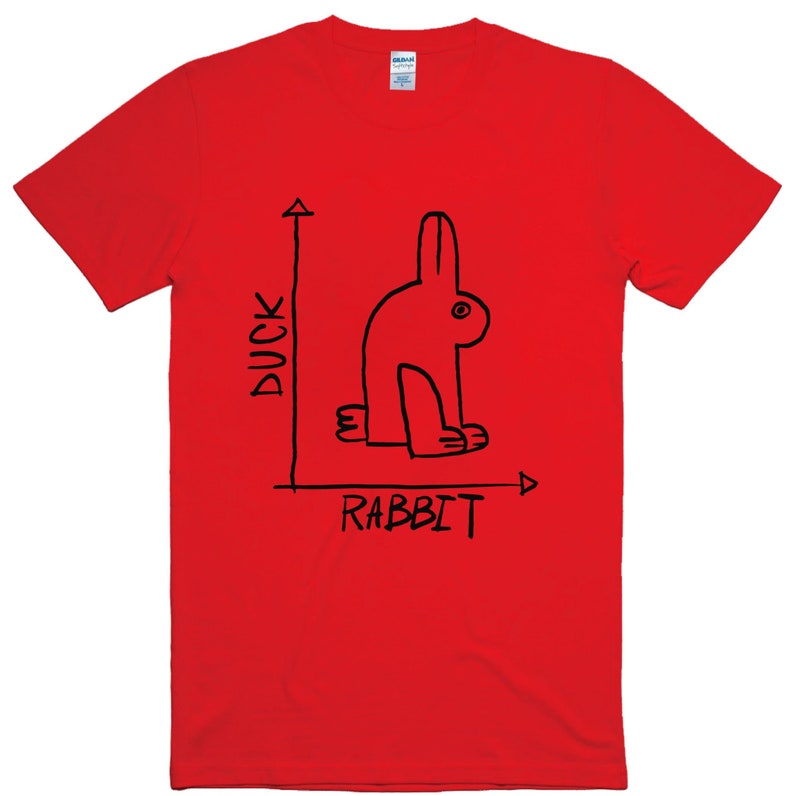May include: A bright red t-shirt featuring a black line drawing of a rabbit that could also be a duck. The words "DUCK" and "RABBIT" are written in black on the shirt, along with a line graph.