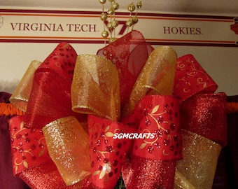 May include: Red and gold Christmas tree topper bow with a gold glitter finish. The bow is decorated with a red and gold ribbon with a floral design. The topper is topped with a gold wire with gold beads.