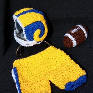 Può includere: Un casco da football, pantaloncini e un pallone da football all'uncinetto in giallo, blu e bianco.
