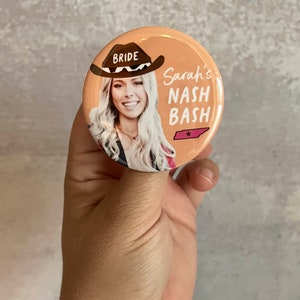 May include: A round button with a peach background features a woman wearing a cowboy hat with the word "BRIDE" on it. The text "Sarah's NASH BASH" is printed in black with a pink star and the state of Tennessee outline.