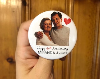 Puede incluir: Un botón blanco con una foto de una pareja, un corazón rojo y el texto "Happy 40th Anniversary MIRANDA & JIM!"