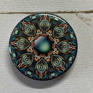 May include: A round, blue, orange, and green mandala design with intricate details. The mandala is printed on a round, white button.