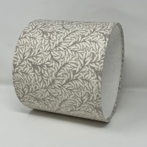 May include: A grey and white patterned lampshade with a white interior. The pattern features a repeating design of leaves and branches.