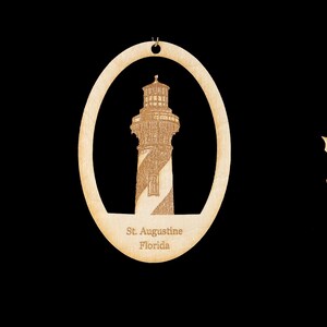 May include: Three wooden ornaments featuring a lighthouse with the text "St. Augustine, Florida" on the bottom. The ornaments are in the shape of a rectangle, oval, and a wreath.