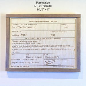 May include: A framed wooden plaque with a light-colored interior, featuring text that reads "Personalize AETC Form 341 8-1/2" x 11". The text includes details like "Excellence/Discrepancy Report" and a farewell message. The frame is a light brown color.