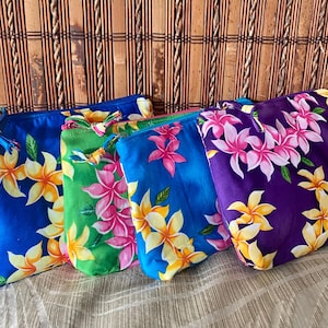 May include: Four colorful zippered pouches with floral patterns. The pouches are in shades of blue, green, and purple, each adorned with pink and yellow flowers. The pouches are made of a silky fabric and are arranged side by side.