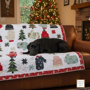 May include: A white Christmas-themed quilt with red trim, featuring appliqued mittens, hats, and Christmas trees. A black dog rests on a brown leather sofa in front of a decorated Christmas tree.