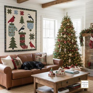 May include: A wall-mounted quilt featuring a cream background with appliqued patterns of red cardinals, black and white birds, green pine trees, and patterned stockings. The quilt is framed by a dark border with small red and green floral accents.