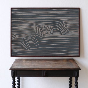 May include: A framed abstract art print with a dark gray background and white lines creating a wavy pattern.