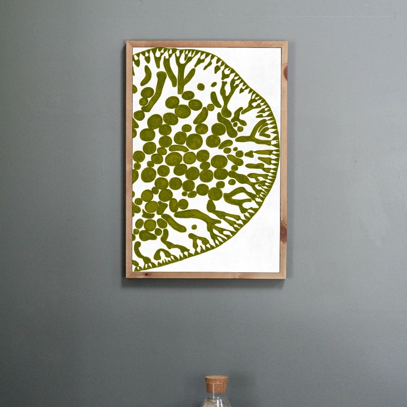 May include: A framed print of a green abstract design with a white background. The design features a large, organic shape with a textured surface and a series of smaller circles.