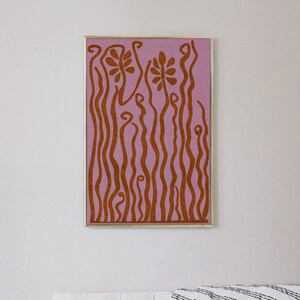 Op de afbeelding: Abstracte kunstprint met een roze achtergrond en bruine organische vormen die lijken op bloemen en stengels.