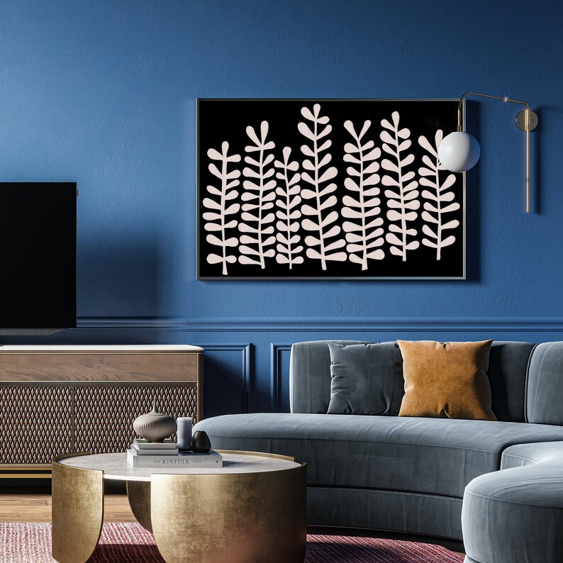 Puede incluir: Una impresi&oacute;n de arte abstracto en blanco y negro con un dise&ntilde;o estilizado de hojas rosas sobre un fondo negro. La impresi&oacute;n est&aacute; enmarcada y colgada en una pared azul sobre un sof&aacute; azul curvo.