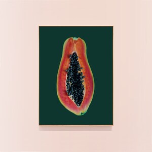May include: A close-up of a papaya cut in half, revealing the black seeds inside. The papaya is a vibrant red and orange color, and the background is a deep green.