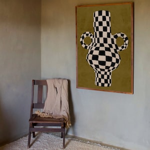 Pode incluir: Um vaso xadrez preto e branco com duas al&ccedil;as, emoldurado contra um fundo verde opaco. O vaso &eacute; uma pe&ccedil;a de arte decorativa.