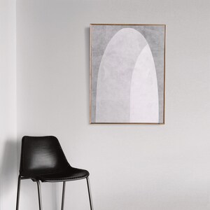 Peut inclure: Une impression d'art abstrait encadr&eacute;e avec un motif g&eacute;om&eacute;trique blanc et gris. L'impression est dans un cadre fin dor&eacute; et est accroch&eacute;e &agrave; un mur blanc.