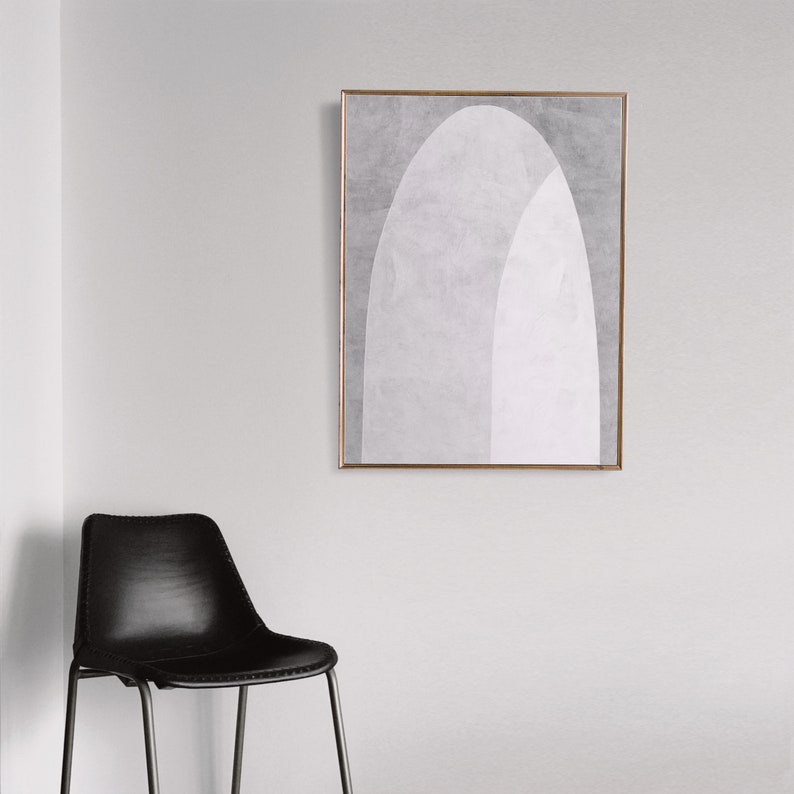 Peut inclure: Une impression d'art abstrait encadr&eacute;e avec un motif g&eacute;om&eacute;trique blanc et gris. L'impression est dans un cadre fin dor&eacute; et est accroch&eacute;e &agrave; un mur blanc.