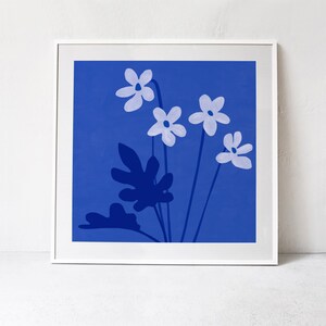 Pu&ograve; includere: Una stampa incorniciata di uno sfondo blu con fiori bianchi e foglie blu scuro. I fiori sono stilizzati e hanno cinque petali ciascuno.