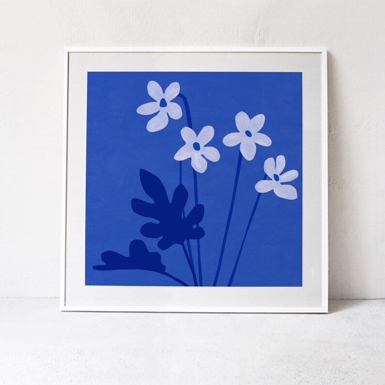 Pu&ograve; includere: Una stampa incorniciata di uno sfondo blu con fiori bianchi e foglie blu scuro. I fiori sono stilizzati e hanno cinque petali ciascuno.